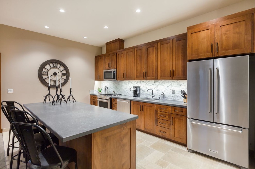 Large country single-wall eat-in kitchen in Other with carpet, beige floor, an undermount sink, shaker cabinets, brown cabinets, concrete benchtops, grey splashback, marble splashback, stainless steel appliances and with island.