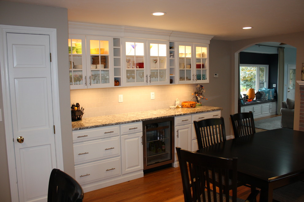 Large transitional l-shaped light wood floor eat-in kitchen photo in Boston with an undermount sink, raised-panel cabinets, white cabinets, granite countertops, gray backsplash, ceramic backsplash, stainless steel appliances and an island