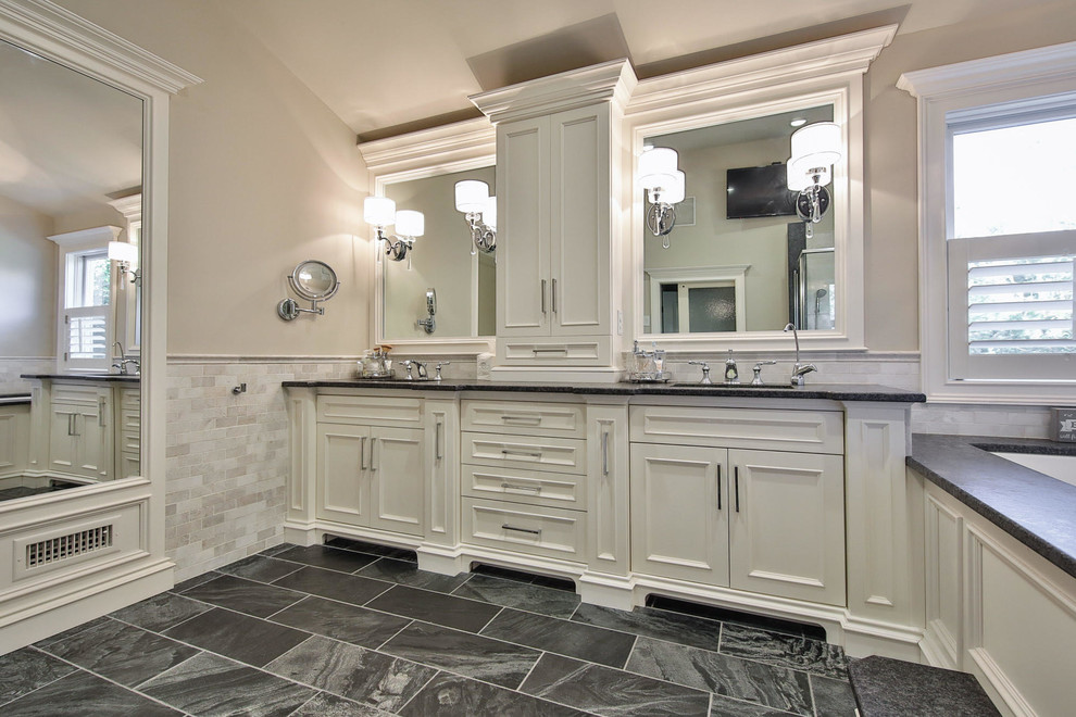 Large transitional master gray tile and marble tile gray floor corner shower photo with beaded inset cabinets, white cabinets, an undermount tub, beige walls, an undermount sink, granite countertops, a hinged shower door and black countertops