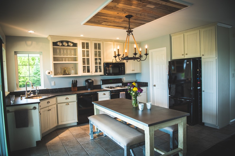 This is an example of a mid-sized country u-shaped open plan kitchen in Other with an undermount sink, shaker cabinets, white cabinets, concrete benchtops, black appliances, ceramic floors, with island and beige floor.