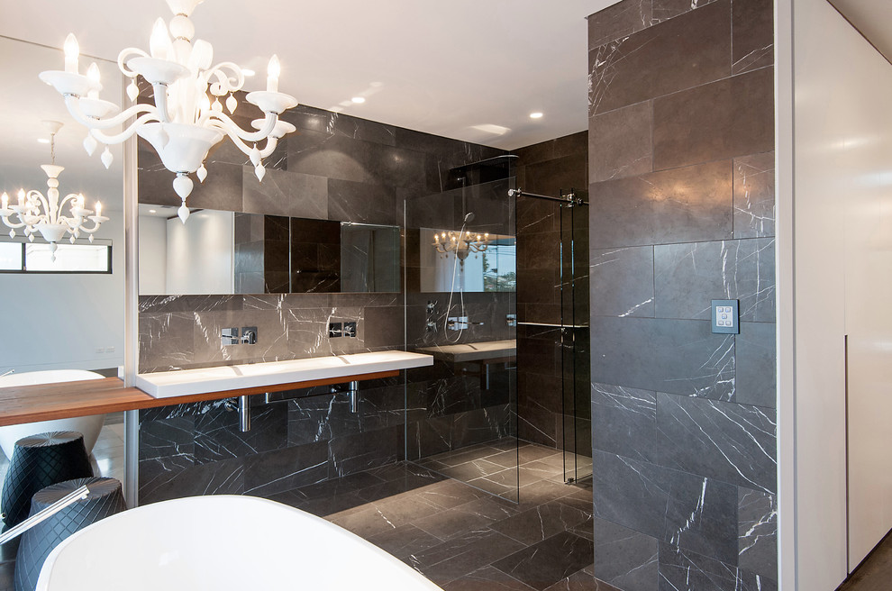 Photo of a large contemporary master bathroom in Sydney with a freestanding tub, a wall-mount toilet, stone tile, grey walls, marble floors, a trough sink, wood benchtops and gray tile.