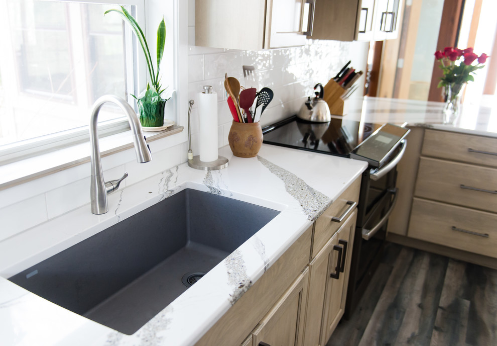 Inspiration for a mid-sized transitional u-shaped vinyl floor and brown floor enclosed kitchen remodel with an undermount sink, flat-panel cabinets, beige cabinets, quartz countertops, white backsplash, subway tile backsplash, black appliances, a peninsula and white countertops