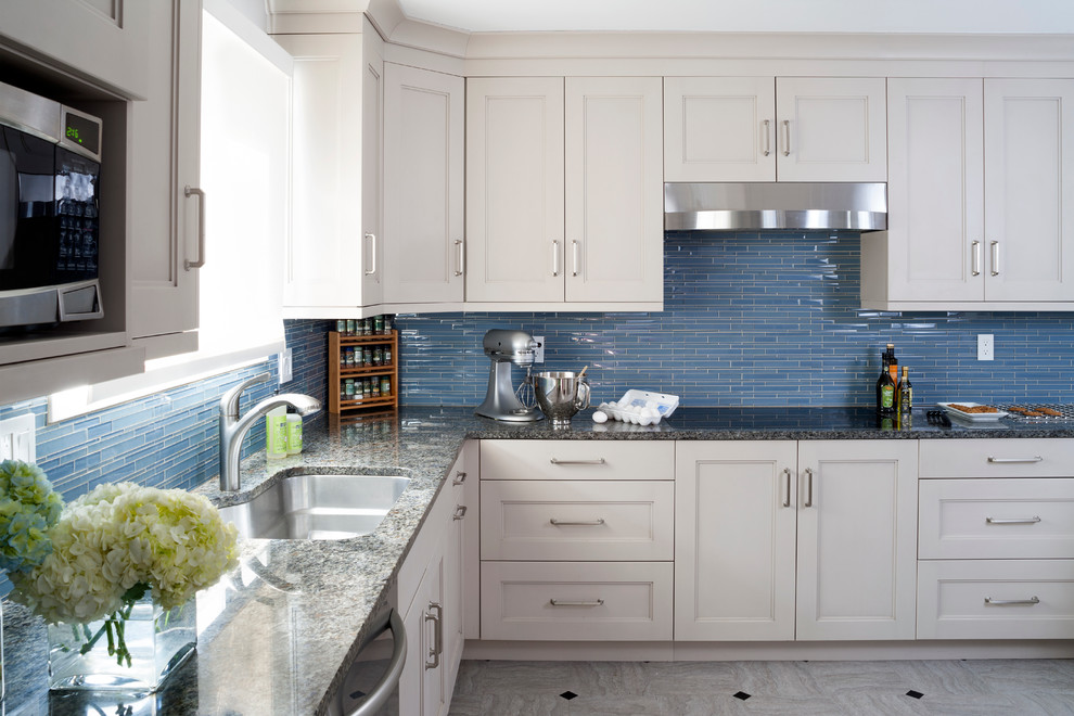 This is an example of a mid-sized transitional u-shaped kitchen in DC Metro with an undermount sink, recessed-panel cabinets, beige cabinets, granite benchtops, blue splashback, glass tile splashback, stainless steel appliances and linoleum floors.