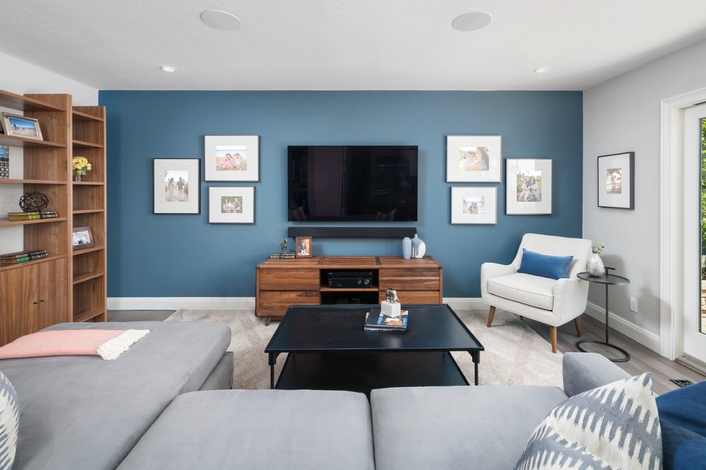Photo of a mid-sized transitional enclosed family room in San Francisco with no fireplace, a wall-mounted tv, grey walls, medium hardwood floors and grey floor.