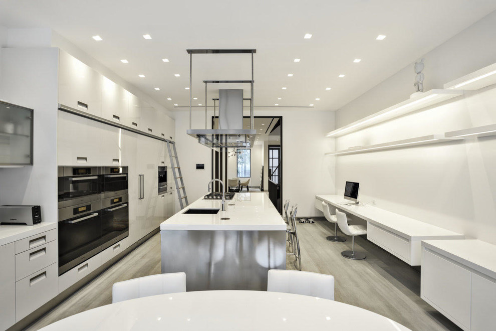 Design ideas for a mid-sized modern u-shaped eat-in kitchen in New York with white cabinets, glass benchtops, with island, an undermount sink, flat-panel cabinets, white splashback, glass sheet splashback, stainless steel appliances, light hardwood floors and beige floor.