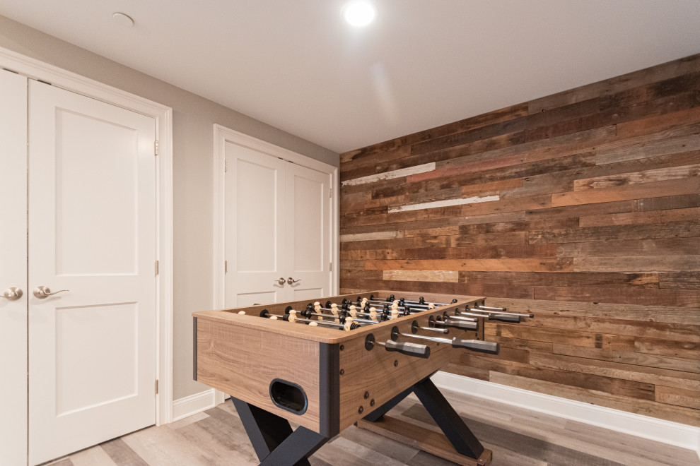 Photo of a large country fully buried basement in Philadelphia with a home bar, grey walls, grey floor and planked wall panelling.