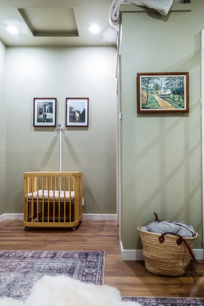Aménagement d'une petite chambre de bébé neutre classique avec un mur vert, un sol en vinyl, un sol marron et un plafond décaissé.