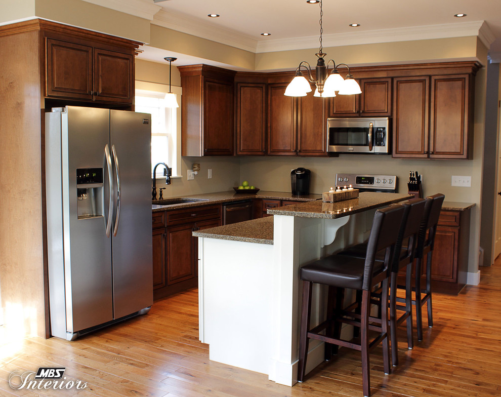 Transitional l-shaped kitchen photo with an undermount sink, recessed-panel cabinets, medium tone wood cabinets, quartz countertops, stainless steel appliances and an island