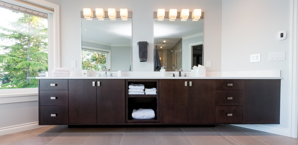 Example of a large transitional master porcelain tile freestanding bathtub design with flat-panel cabinets, dark wood cabinets, gray walls, an undermount sink, a hinged shower door, quartz countertops and white countertops