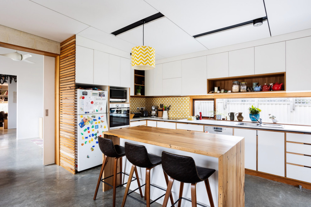 Inspiration för mellanstora moderna vitt kök, med en dubbel diskho, vita skåp, träbänkskiva, gult stänkskydd, stänkskydd i cementkakel, rostfria vitvaror, betonggolv, en köksö och grått golv