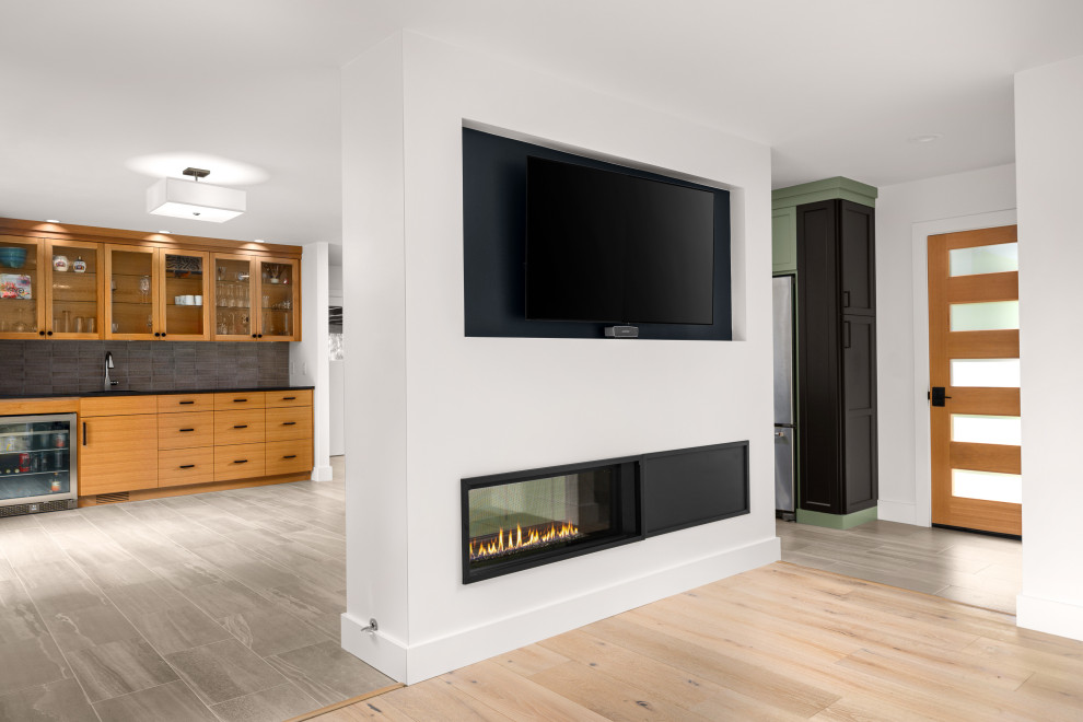 Foto de salón abierto retro de tamaño medio con paredes blancas, suelo de madera clara, chimenea de doble cara y televisor colgado en la pared