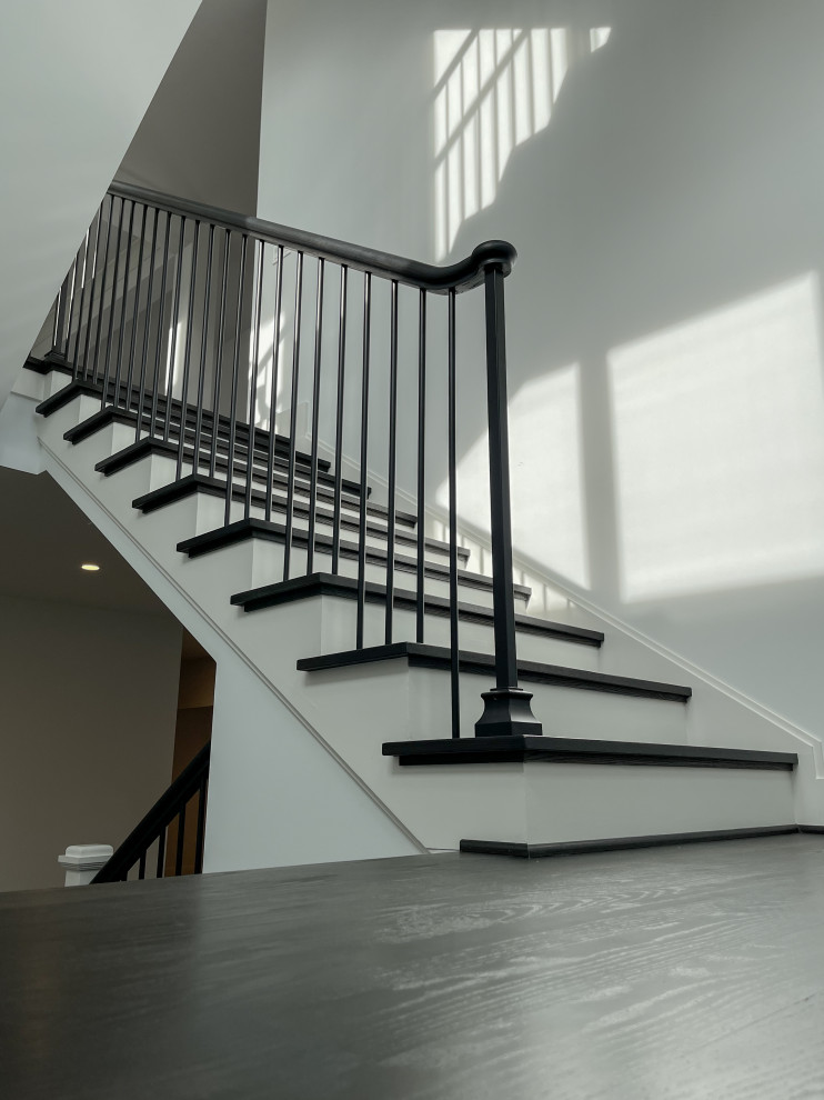 Photo of a large transitional wood floating staircase in DC Metro with wood risers, mixed railing and panelled walls.