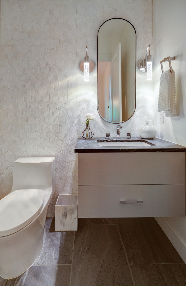 Пример оригинального дизайна: маленький туалет в стиле модернизм с плоскими фасадами, белыми фасадами, унитазом-моноблоком, белой плиткой, мраморной плиткой, белыми стенами, полом из керамической плитки, врезной раковиной, столешницей из талькохлорита, серым полом, черной столешницей и подвесной тумбой для на участке и в саду