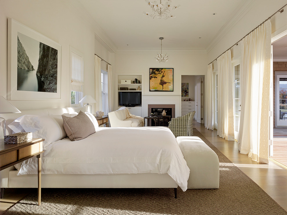 Large transitional master bedroom in San Francisco with white walls, light hardwood floors and a standard fireplace.