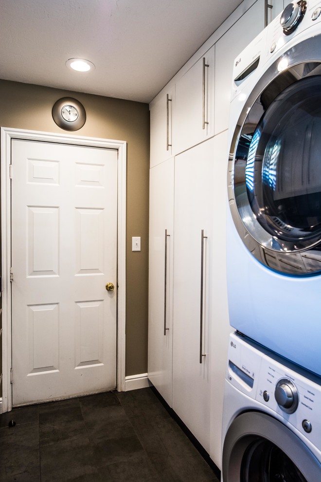 Design ideas for a mid-sized contemporary single-wall laundry room in Salt Lake City with flat-panel cabinets, white cabinets, solid surface benchtops, slate floors and black floor.
