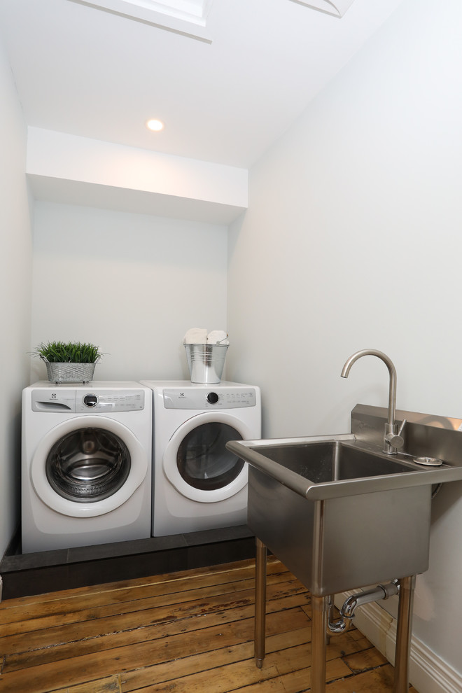 Dedicated laundry room - mid-sized transitional single-wall white tile medium tone wood floor and brown floor dedicated laundry room idea with a one-piece toilet, an undermount sink, gray countertops, an utility sink, white walls and a side-by-side washer/dryer