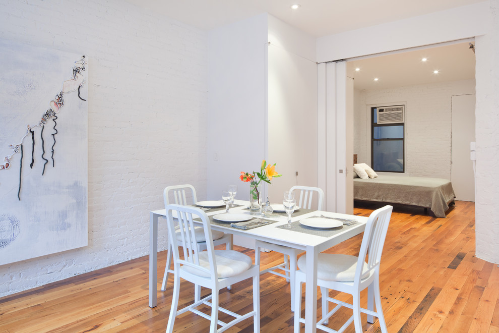 Photo of a contemporary dining room in New York with white walls and medium hardwood floors.