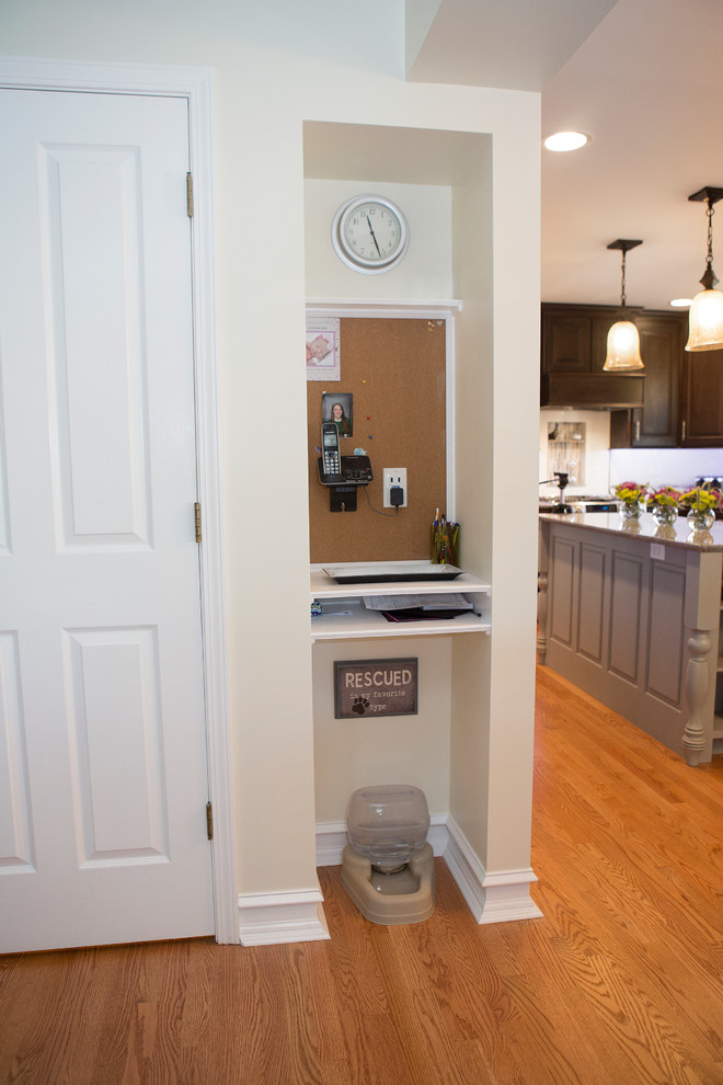 Enclosed kitchen - mid-sized transitional u-shaped light wood floor enclosed kitchen idea in Chicago with an undermount sink, raised-panel cabinets, dark wood cabinets, quartz countertops, beige backsplash, ceramic backsplash, stainless steel appliances and an island