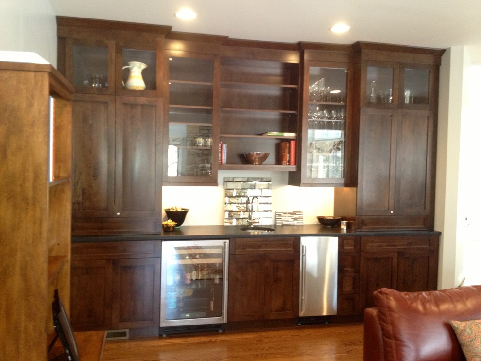 Design ideas for a mid-sized traditional single-wall wet bar in Philadelphia with an undermount sink, shaker cabinets, dark wood cabinets, solid surface benchtops and dark hardwood floors.