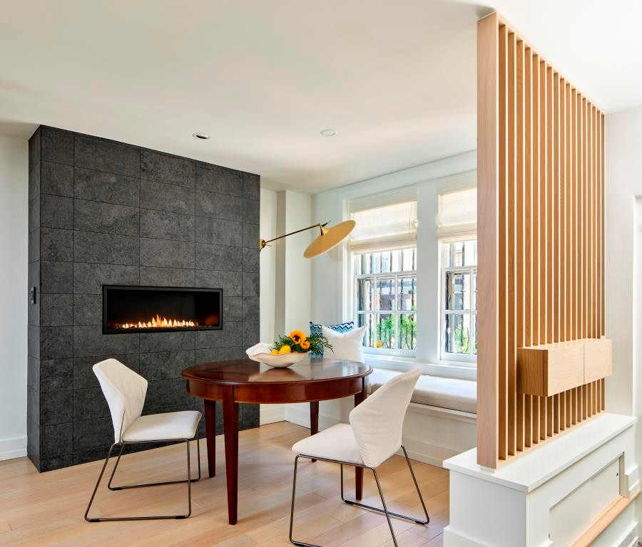 Inspiration for a small modern dining room in Philadelphia with banquette seating, light hardwood flooring, a ribbon fireplace, a tiled fireplace surround and beige floors.