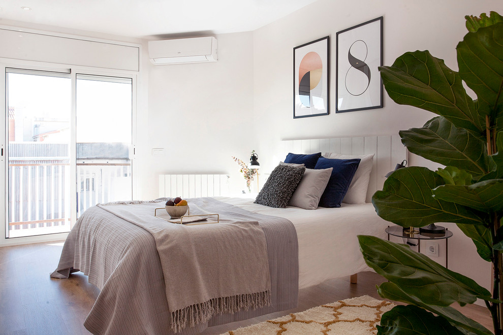 This is an example of a scandinavian guest bedroom in Barcelona with white walls, medium hardwood floors and brown floor.