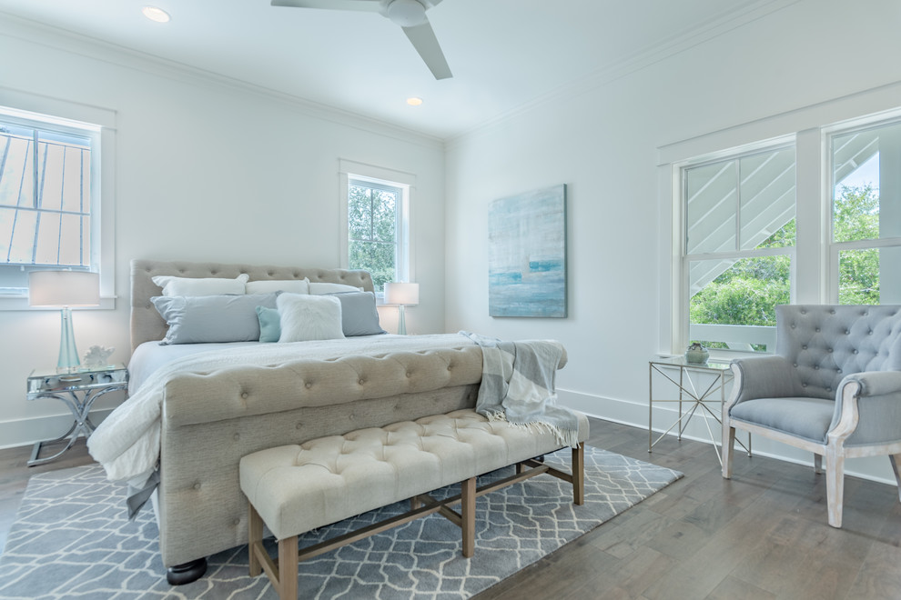 Photo of a mid-sized beach style master bedroom in Other with white walls, medium hardwood floors, brown floor and no fireplace.