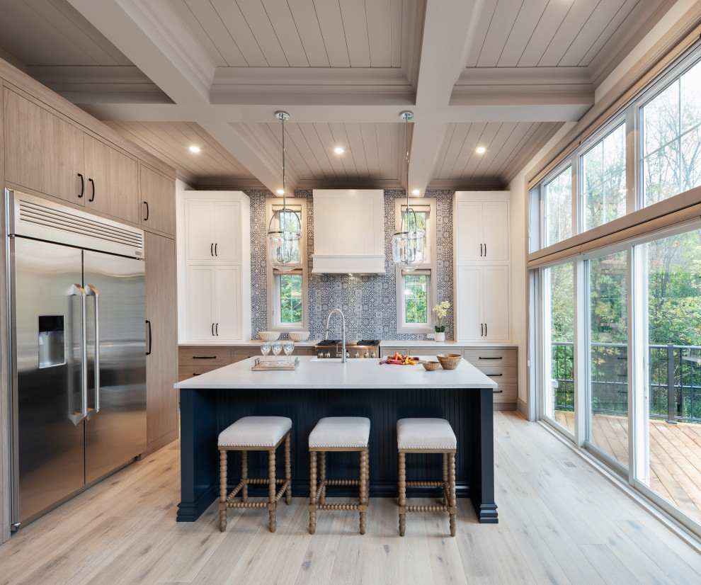Transitional u-shaped kitchen in Ottawa with a farmhouse sink, flat-panel cabinets, light wood cabinets, blue splashback, stainless steel appliances, light hardwood floors, with island, beige floor, white benchtop and coffered.