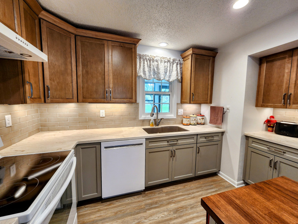 Eat-in kitchen - mid-sized transitional l-shaped vinyl floor and multicolored floor eat-in kitchen idea with an undermount sink, shaker cabinets, solid surface countertops, beige backsplash, subway tile backsplash, white appliances, an island and white countertops