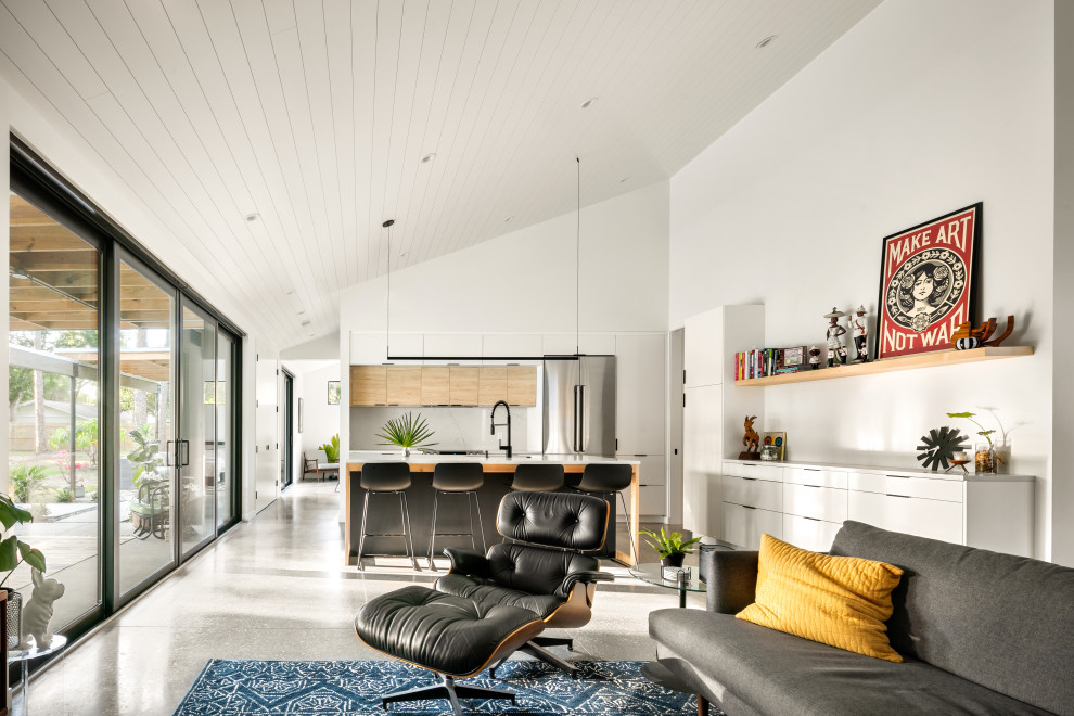 Ejemplo de salón abierto contemporáneo de tamaño medio sin chimenea con paredes blancas, suelo de cemento, televisor colgado en la pared, suelo gris y machihembrado
