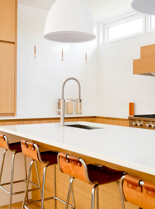 This is an example of a large modern l-shaped eat-in kitchen in New York with a double-bowl sink, flat-panel cabinets, light wood cabinets, terrazzo benchtops, white splashback, marble splashback, panelled appliances, light hardwood floors, with island and brown floor.