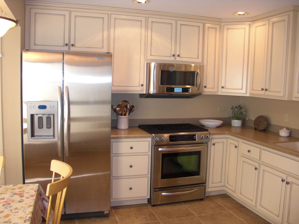 This is an example of a small traditional l-shaped eat-in kitchen in Chicago with an undermount sink, recessed-panel cabinets, white cabinets, granite benchtops, stainless steel appliances, ceramic floors and no island.