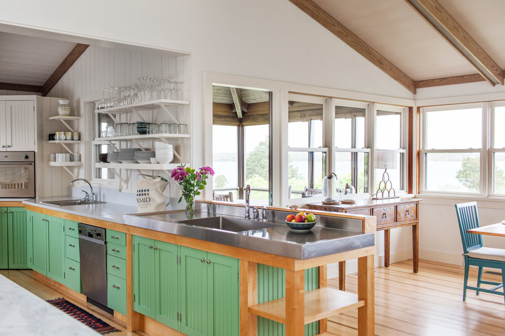 Photo of a mid-sized beach style eat-in kitchen in Boston with beaded inset cabinets, green cabinets, grey splashback, medium hardwood floors, an undermount sink and black appliances.