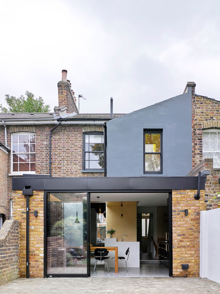 Mid-sized contemporary three-storey brick beige townhouse exterior in London.