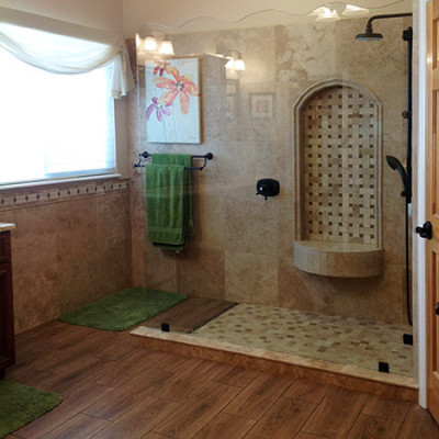 Inspiration for a mid-sized mediterranean master bathroom in Denver with raised-panel cabinets, medium wood cabinets, a corner shower, a two-piece toilet, beige tile, travertine, beige walls, medium hardwood floors, an undermount sink, marble benchtops, brown floor and an open shower.