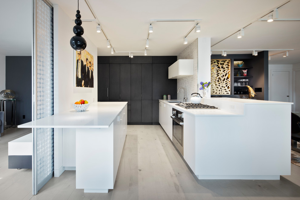 Mid-sized contemporary eat-in kitchen in New York with stainless steel appliances, beige floor, an undermount sink, flat-panel cabinets, white cabinets, quartz benchtops, white splashback, ceramic splashback, light hardwood floors and white benchtop.