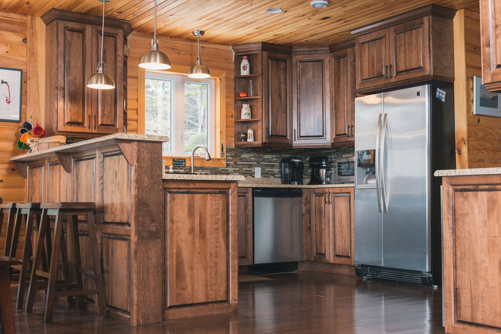 Example of a mid-sized mountain style l-shaped dark wood floor and brown floor eat-in kitchen design with raised-panel cabinets, medium tone wood cabinets, laminate countertops, multicolored backsplash, stainless steel appliances, beige countertops and a peninsula