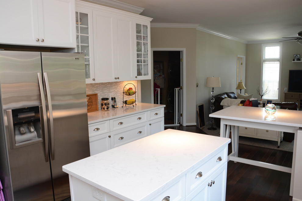 This is an example of a large traditional u-shaped eat-in kitchen in DC Metro with a double-bowl sink, recessed-panel cabinets, white cabinets, quartz benchtops, grey splashback, stainless steel appliances, dark hardwood floors, multiple islands, brown floor and white benchtop.