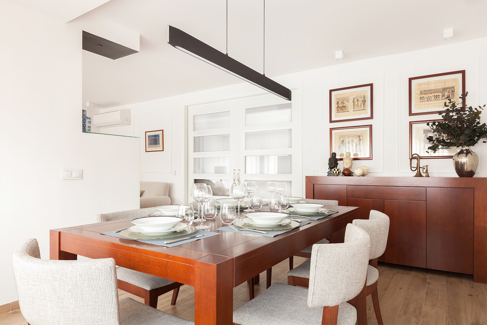 Mid-sized contemporary separate dining room in Madrid with white walls and light hardwood floors.