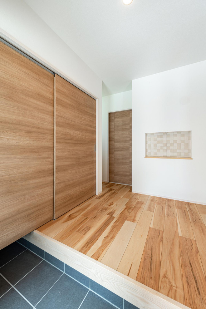 Idée de décoration pour une entrée avec un couloir, un mur blanc, parquet clair, un sol marron, un plafond en papier peint et du papier peint.