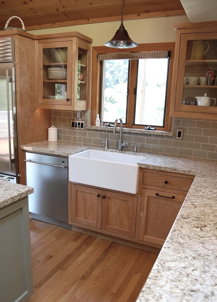 Mid-sized country l-shaped eat-in kitchen in Los Angeles with a farmhouse sink, shaker cabinets, light wood cabinets, granite benchtops, grey splashback, subway tile splashback, stainless steel appliances, light hardwood floors and with island.