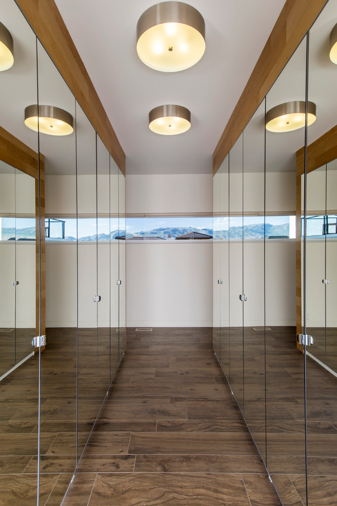 Photo of a contemporary walk-in wardrobe in Vancouver with glass-front cabinets and dark hardwood floors.