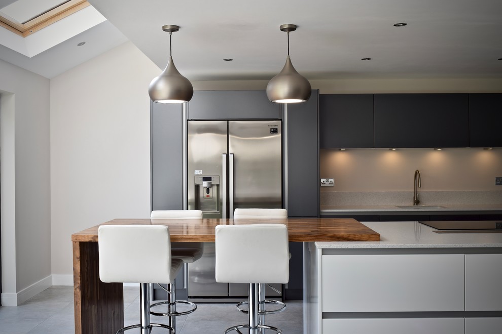 Photo of a mid-sized contemporary single-wall open plan kitchen in West Midlands with grey cabinets, quartzite benchtops, ceramic floors, with island, an undermount sink, flat-panel cabinets, stainless steel appliances, grey floor and grey benchtop.