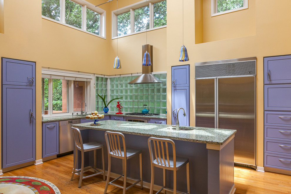 This is an example of a mid-sized eclectic l-shaped open plan kitchen in San Francisco with an undermount sink, flat-panel cabinets, blue cabinets, terrazzo benchtops, glass tile splashback, stainless steel appliances, medium hardwood floors and with island.