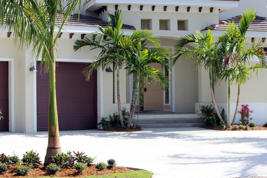 This is an example of a mid-sized tropical one-storey stucco white house exterior in Miami with a hip roof and a shingle roof.