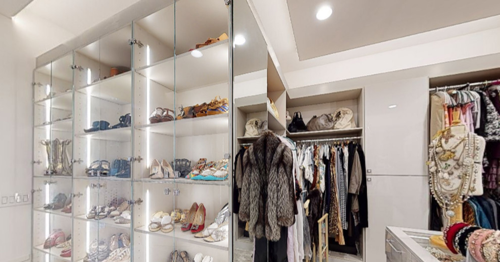 Inspiration for a large modern women's storage and wardrobe in Orange County with glass-front cabinets, grey cabinets, carpet, grey floor and recessed.