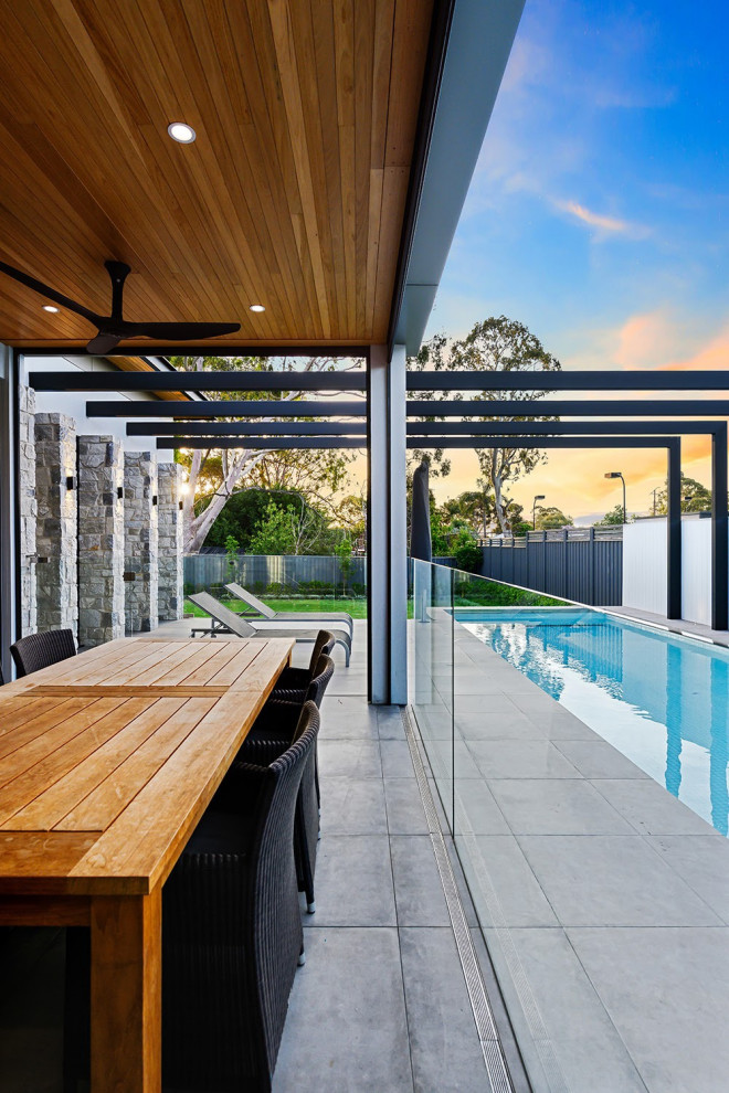 Cette image montre une grande terrasse arrière minimaliste avec une extension de toiture.