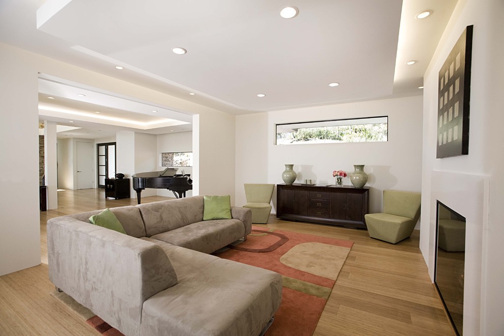 Contemporary open concept family room in San Francisco with white walls, bamboo floors and a standard fireplace.
