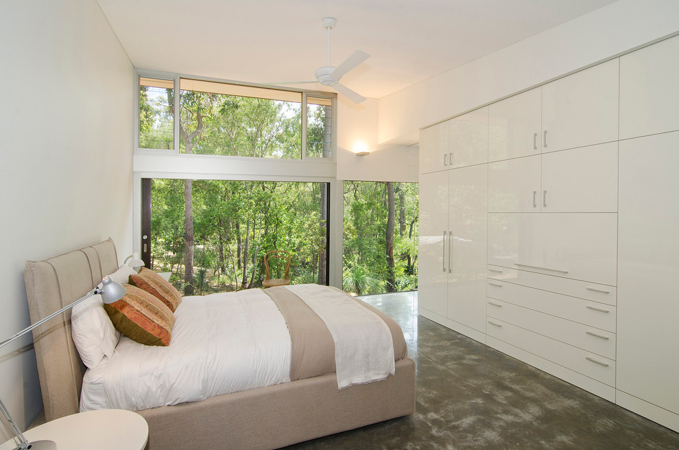Contemporary master bedroom in Perth with white walls and concrete floors.