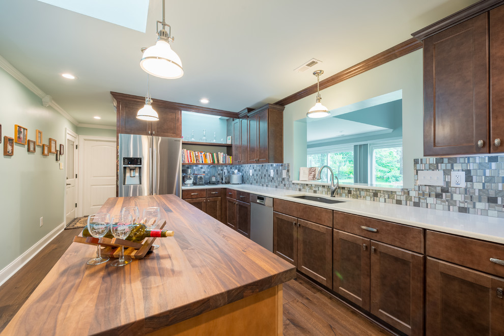 Inspiration for a mid-sized dark wood floor eat-in kitchen remodel with shaker cabinets, brown cabinets, glass tile backsplash, stainless steel appliances and an island