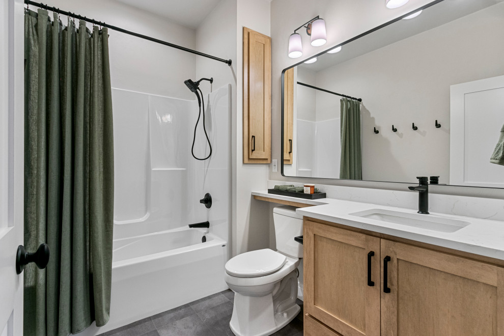 Mid-sized transitional 3/4 vinyl floor, gray floor and single-sink tub/shower combo photo with shaker cabinets, medium tone wood cabinets, a one-piece toilet, white walls, an undermount sink, quartz countertops, white countertops and a built-in vanity
